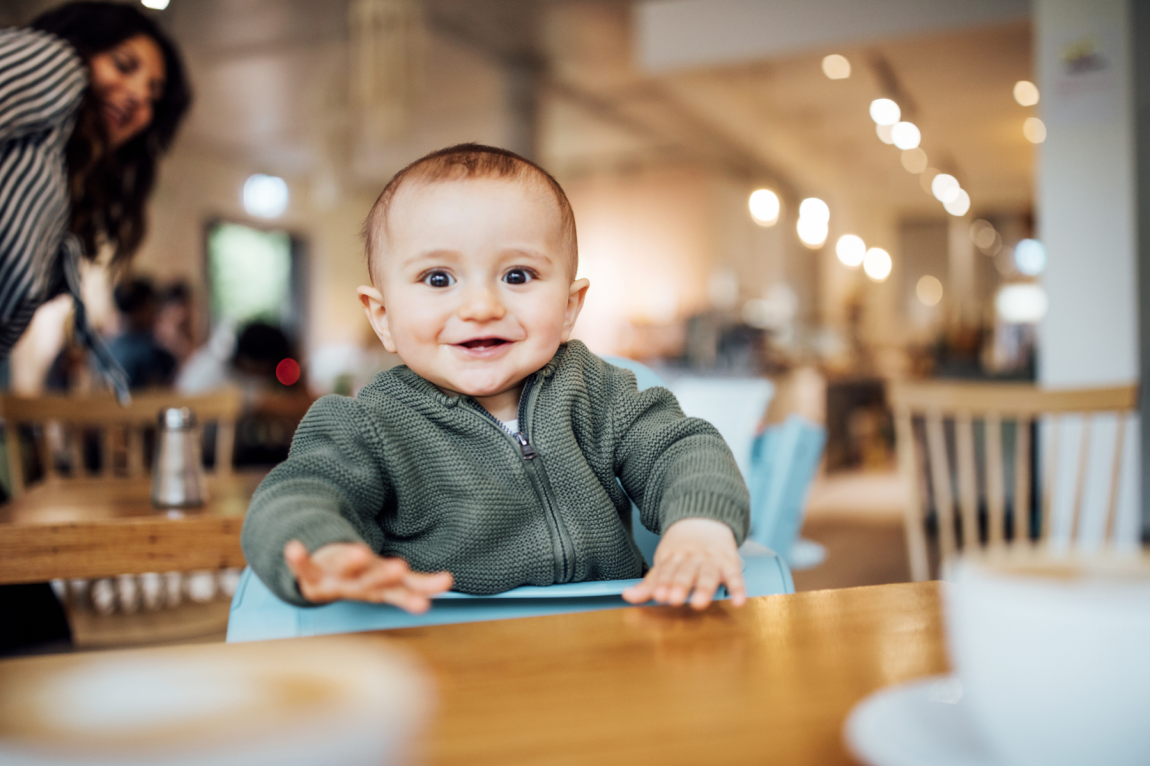 Portrait of cute little baby boy sitting at cafe table.